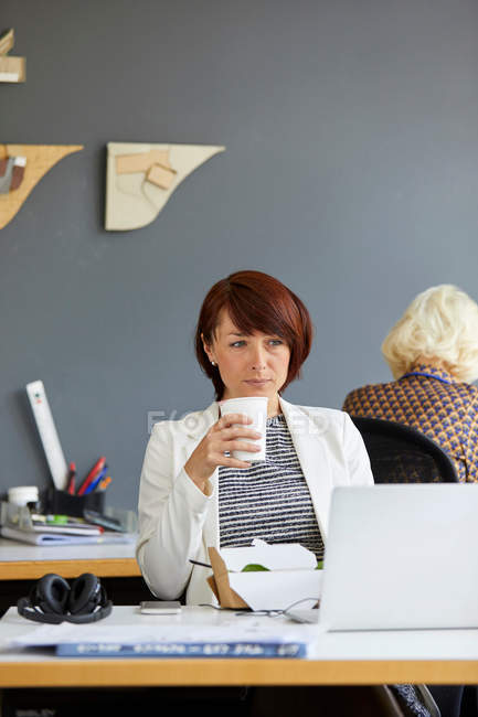 Designer feminino olhando para laptop — Fotografia de Stock