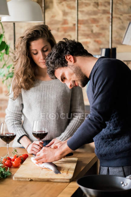 Couple préparant du poisson au comptoir de cuisine — Photo de stock