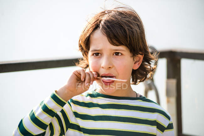Boy finishing ice lolly in park — Stock Photo