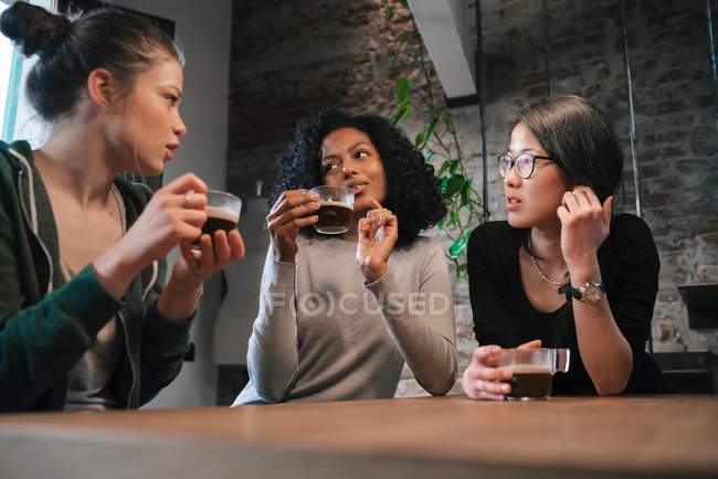 Friends drinking coffee at table — Stock Photo