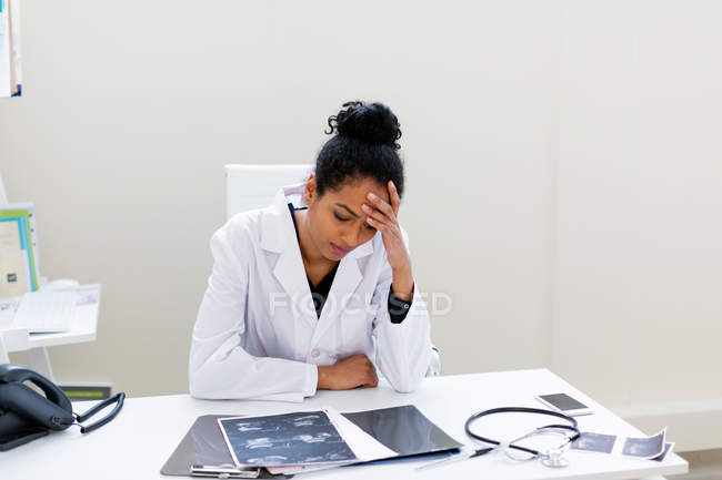 Doctor at desk, head in hand — Stock Photo