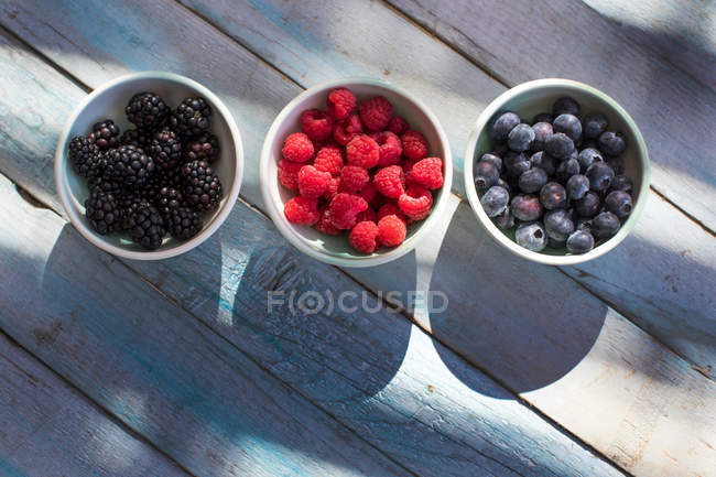 Bols contenant des mûres, des framboises et des bleuets — Photo de stock