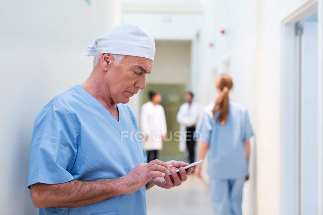 Médico no hospital olhando para o telefone móvel — Fotografia de Stock