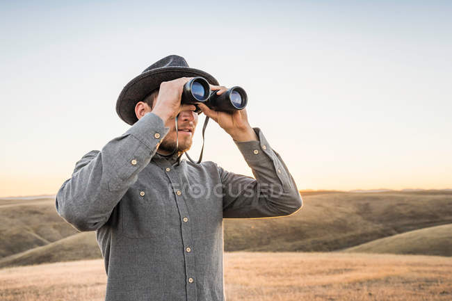 Mann blickt durch Fernglas — Stockfoto