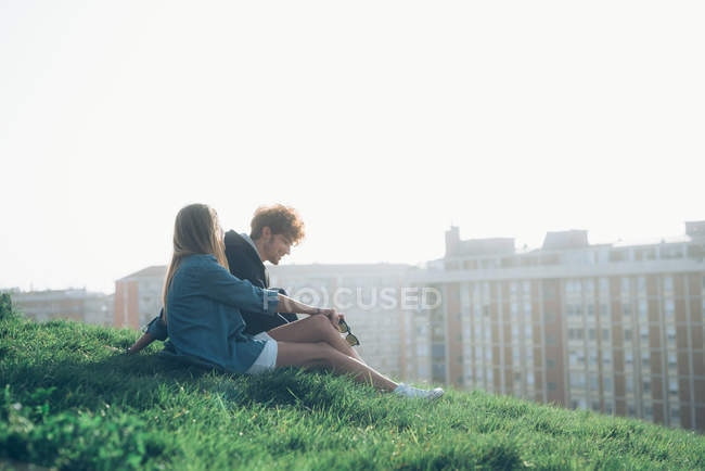 Jovem casal sentado na beira gramado — Fotografia de Stock
