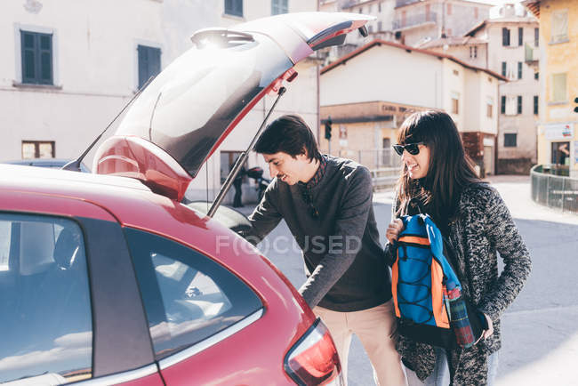 Couple unpacking car boot in village — Stock Photo