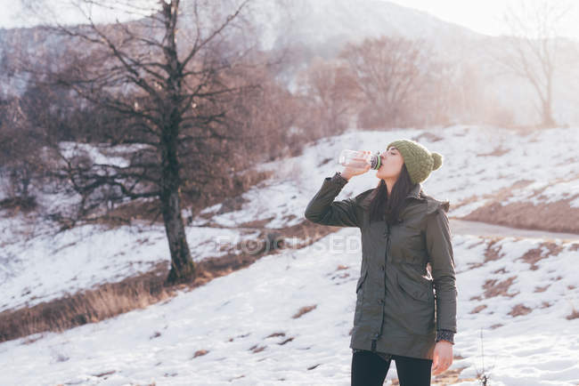 Escursionista donna acqua potabile nella neve — Foto stock