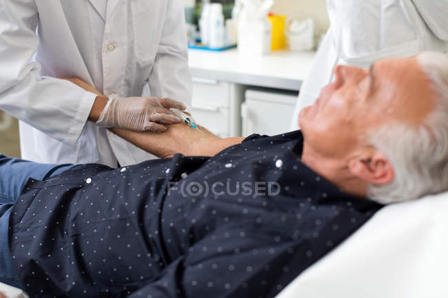 Doctor extracting patient's blood with syringe — Stock Photo