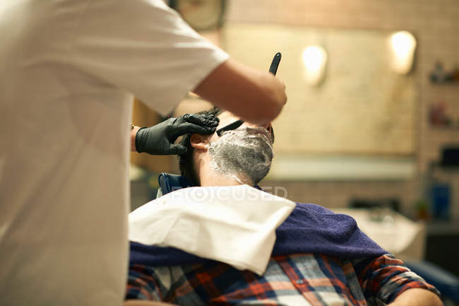 Peluquería dando cliente afeitado húmedo - foto de stock