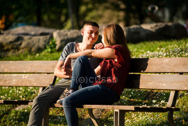 Пара сидящая на скамейке в парке — стоковое фото