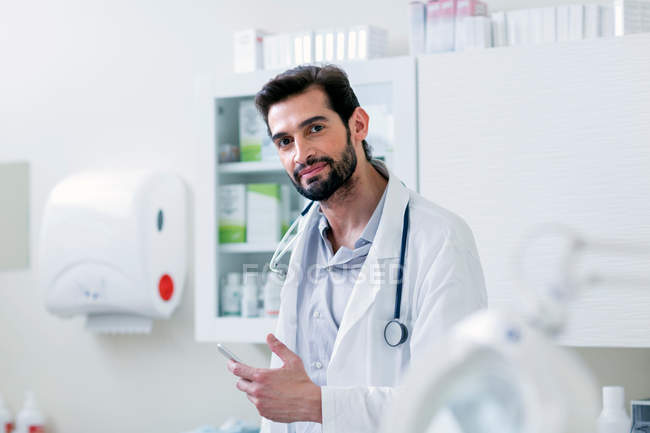 Doctor in hospital holding mobile phone — Stock Photo