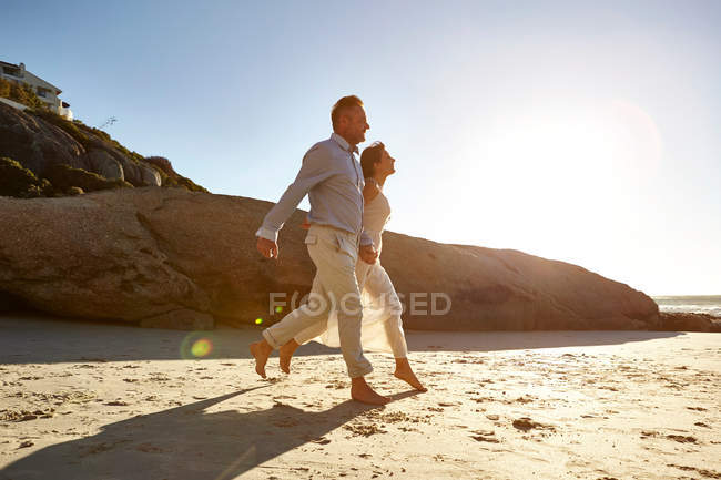 Casal maduro correndo ao longo da praia — Fotografia de Stock