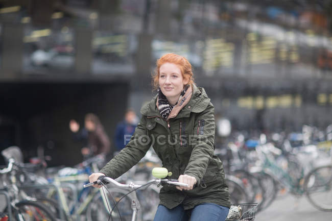 Estudiante en bicicleta lejos de la Biblioteca Universitaria - foto de stock