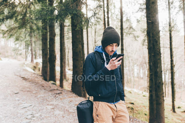 Чоловічий пішохід, дивлячись на смартфон у лісі — стокове фото