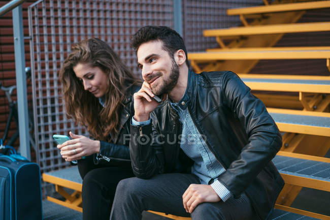 Couple assis sur les marches avec des bagages — Photo de stock