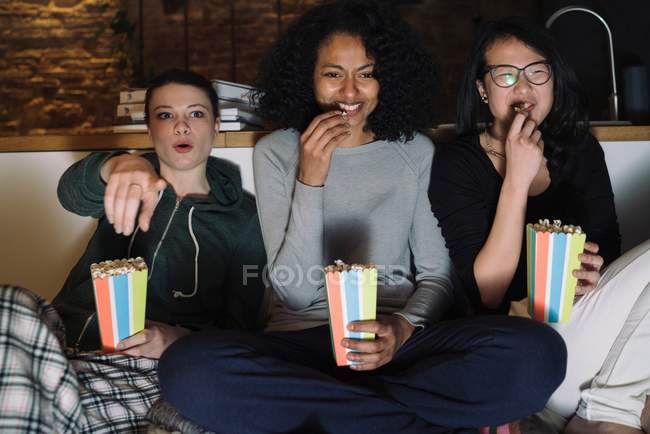 Друзья на диване едят попкорн — стоковое фото
