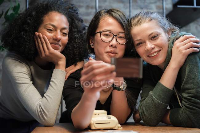 Friends looking at instant film photograph — Stock Photo