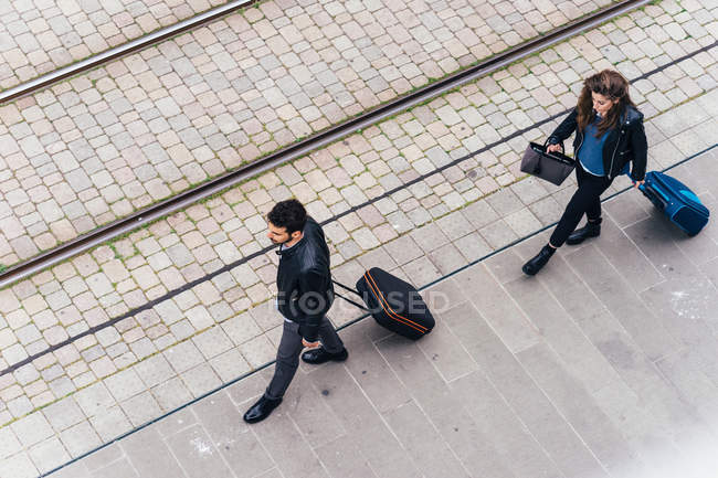 Pareja caminando con equipaje en la calle de la ciudad - foto de stock