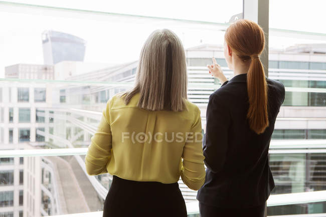 Деловые женщины, стоящие у окна в офисе — стоковое фото