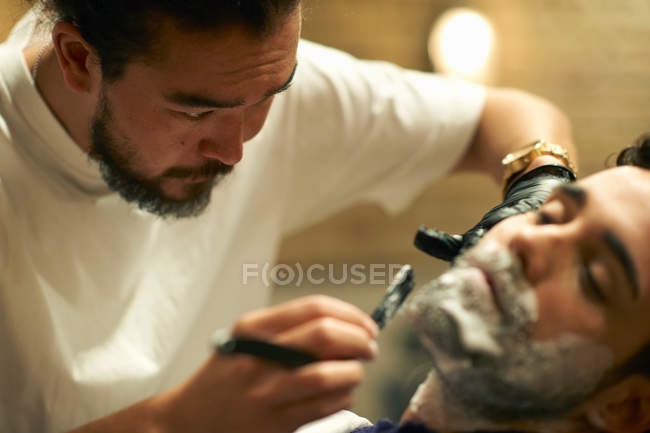 Hairdresser giving customer wet shave — Stock Photo