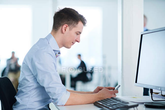 Businessman in office using mobile phone — Stock Photo
