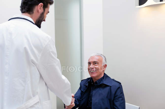 Paciente estrechando la mano con el médico - foto de stock
