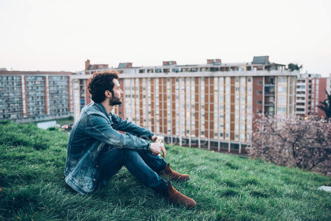 Jeune homme assis sur le toit jardin — Photo de stock