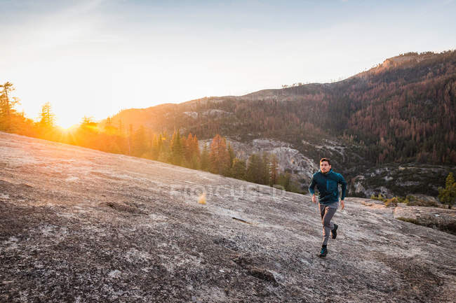 Человек бежит по поверхности скалы на закате — стоковое фото