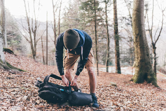 Male hiker unpacking backpack in forest — Stock Photo
