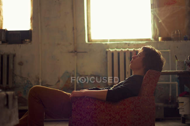 Junger Mann sitzt auf Vintage-Sessel — Stockfoto