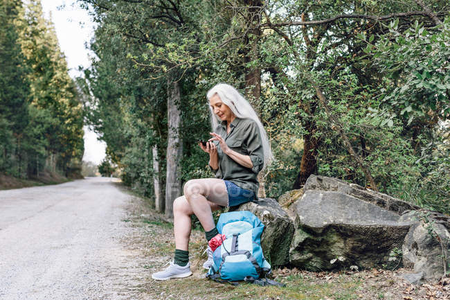 Female backpacker looking at smartphone — Stock Photo