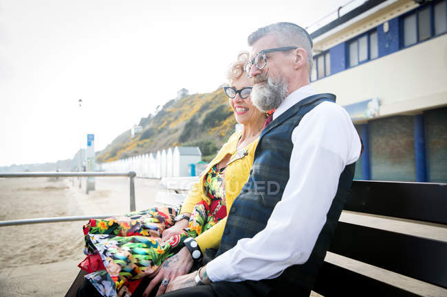Пара, выглядывающая с пляжной скамьи — стоковое фото