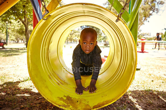 Rapaz no túnel rastejante no parque infantil — Fotografia de Stock