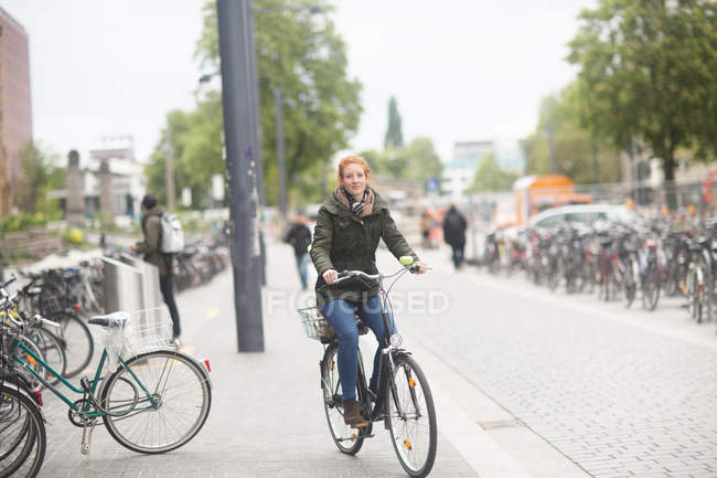 Student cycling away from library — Stock Photo