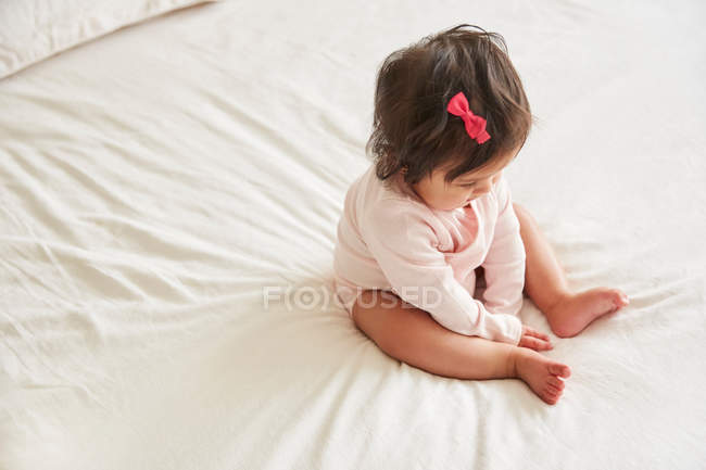 Bebê menina sentado em cima da cama — Fotografia de Stock