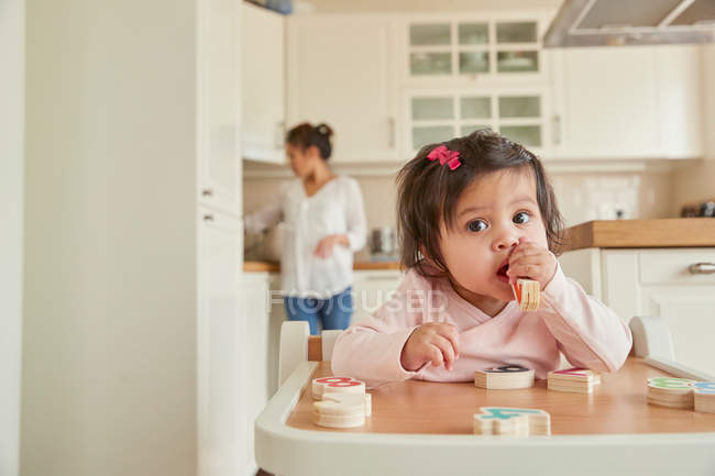 Девочка жует игрушечные цифры — стоковое фото