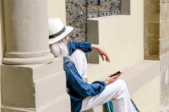 Mature woman sitting outside church — Stock Photo