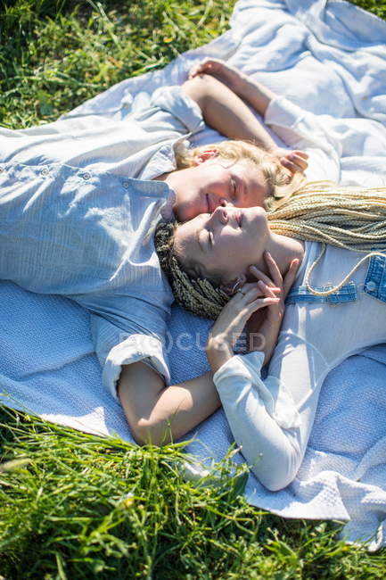 Пара лежит на одеяле для пикника в траве — стоковое фото