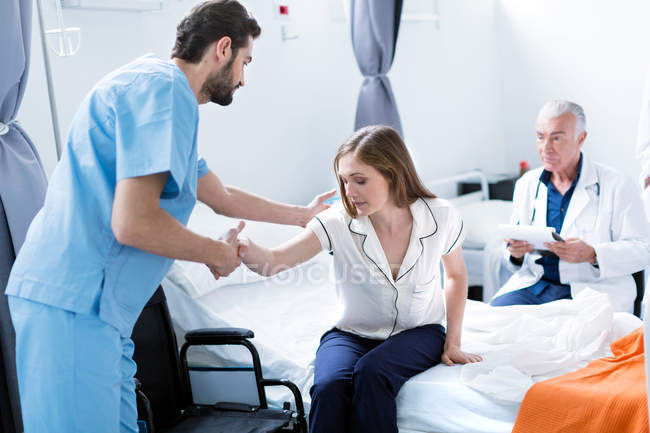 Doctor helping patient out of hospital bed — Stock Photo