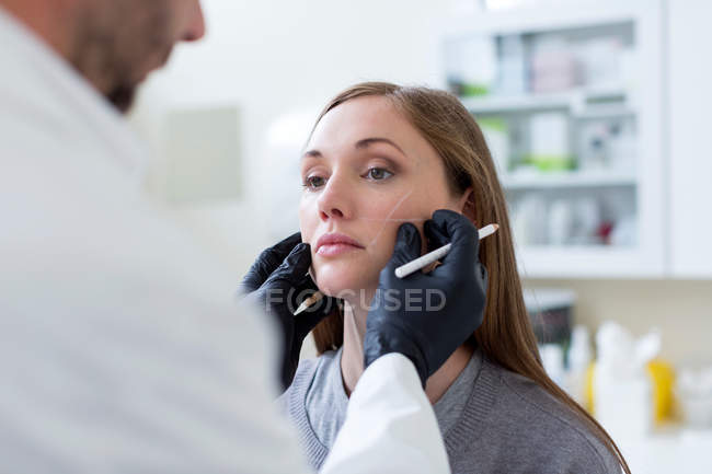 Cirurgião cosmético marcando o rosto do paciente para cirurgia — Fotografia de Stock