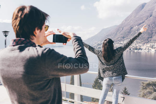 Чоловік фотографує дівчину на березі озера — стокове фото