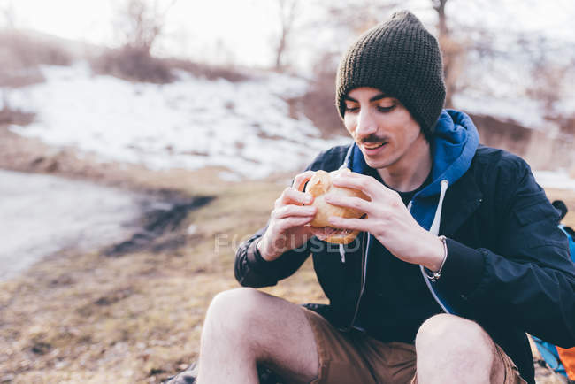 Hiker on roadside eating sandwich — Stock Photo