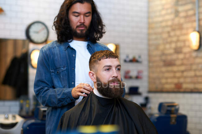 Hairdresser putting protective cape — Stock Photo