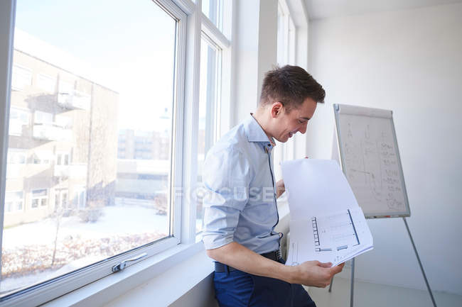 Architect in office looking at blueprint — Stock Photo