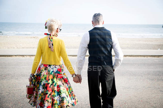 Coppia che si tiene per mano e passeggia sulla spiaggia — Foto stock