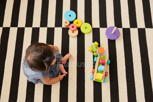 Bebê menina sentado no tapete — Fotografia de Stock