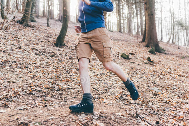 Male runner running in steep forest — Stock Photo