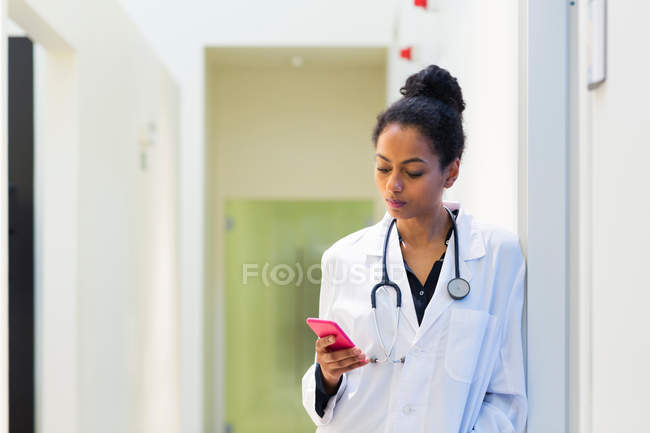 Médico olhando para o telefone móvel — Fotografia de Stock