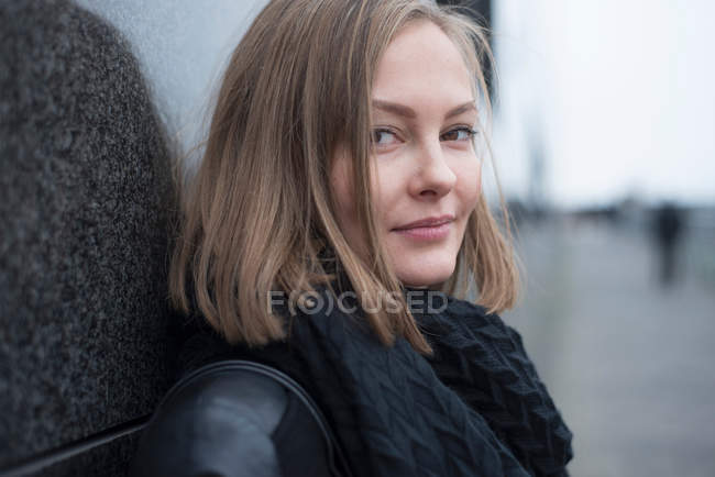 Young woman leaning against wall — Stock Photo