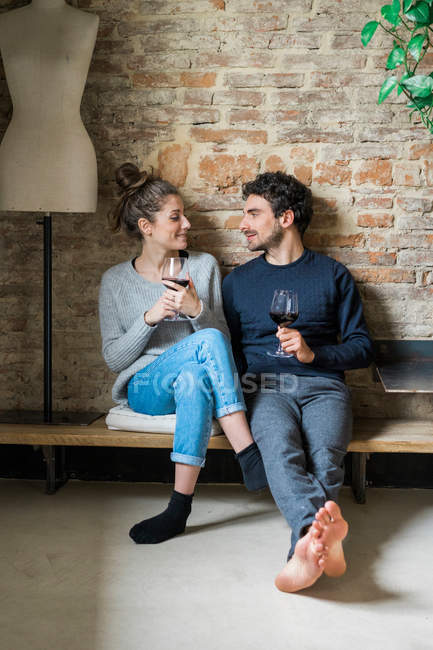 Couple sitting on bench with red wine — Stock Photo